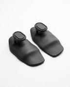 Pair of black silicone grip pads on light grey studio surface