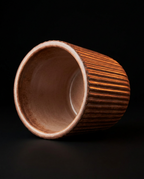 Brown ribbed holder cup tipped on its side showing the smooth interior