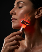 Woman gliding the warm red light wand along her jawline with heat waves