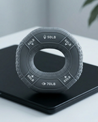 Dark gray grip strengthener ring standing upright on a black tray