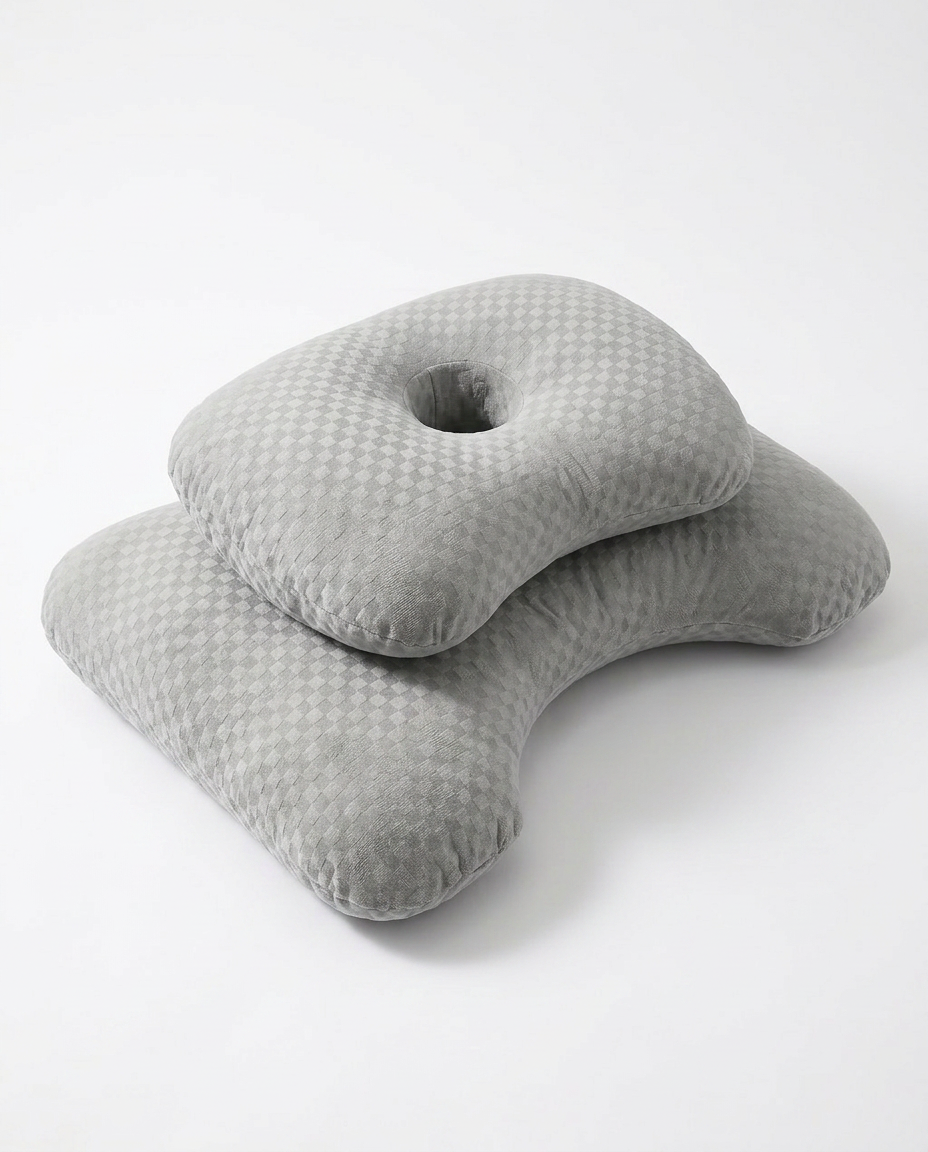 Grey ergonomic sleep pillow with grid-textured cover and ear cutout, studio shot
