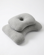 Grey ergonomic sleep pillow with grid-textured cover and ear cutout, studio shot