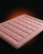 Dusty pink quilted floor mattress on a dark backdrop with orange glow