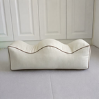 Cream contoured leg elevation pillow with wavy top, side view on white