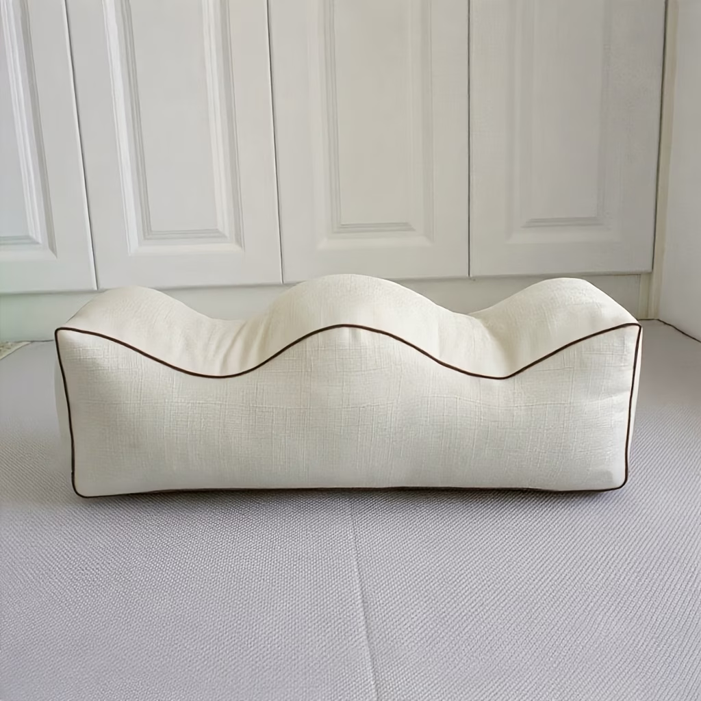 Cream contoured leg elevation pillow with wavy top, side view on white