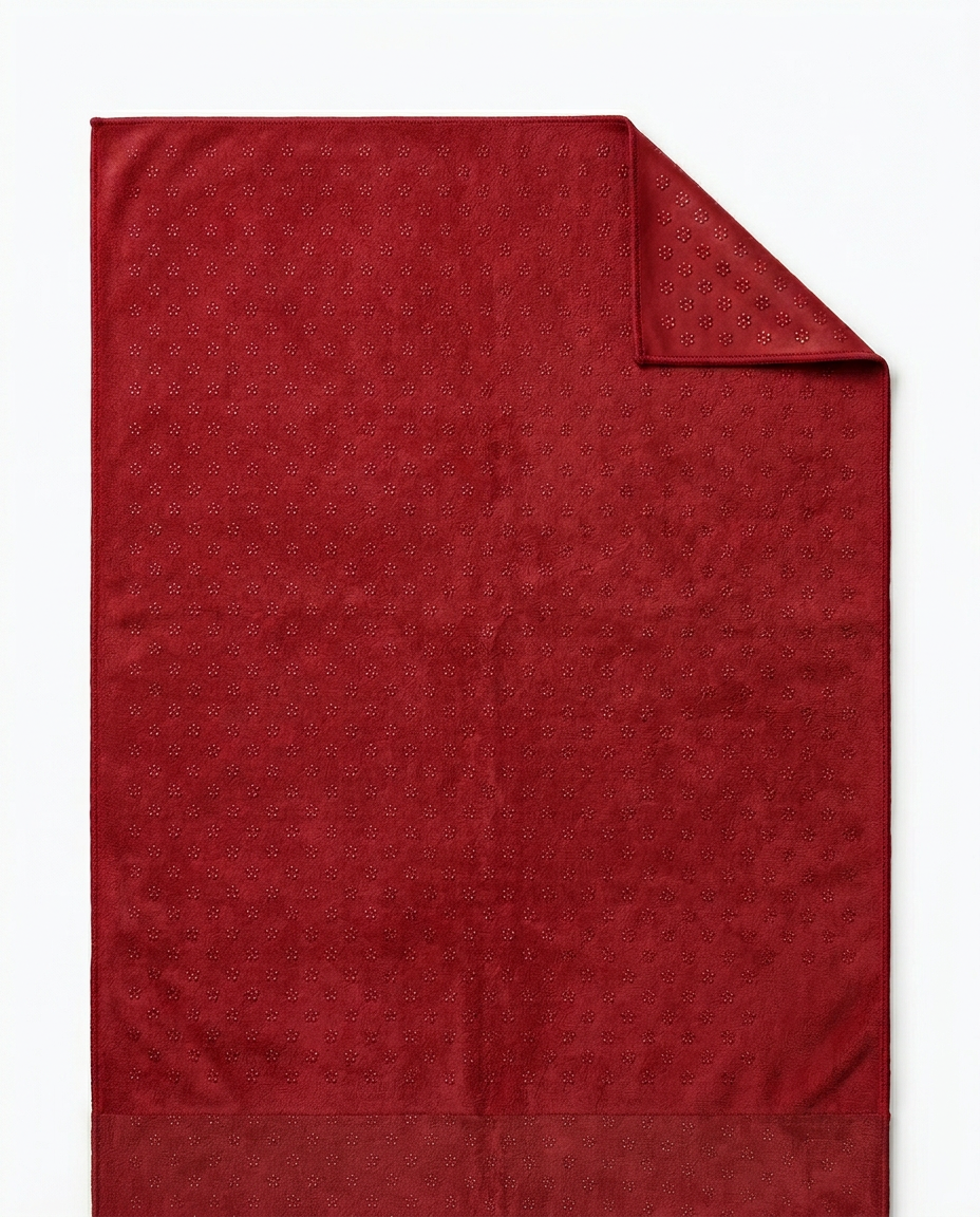 Deep red yoga towel flat-laid with top corner folded back