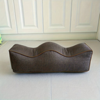 Brown linen leg support pillow with contoured top and piping, side view