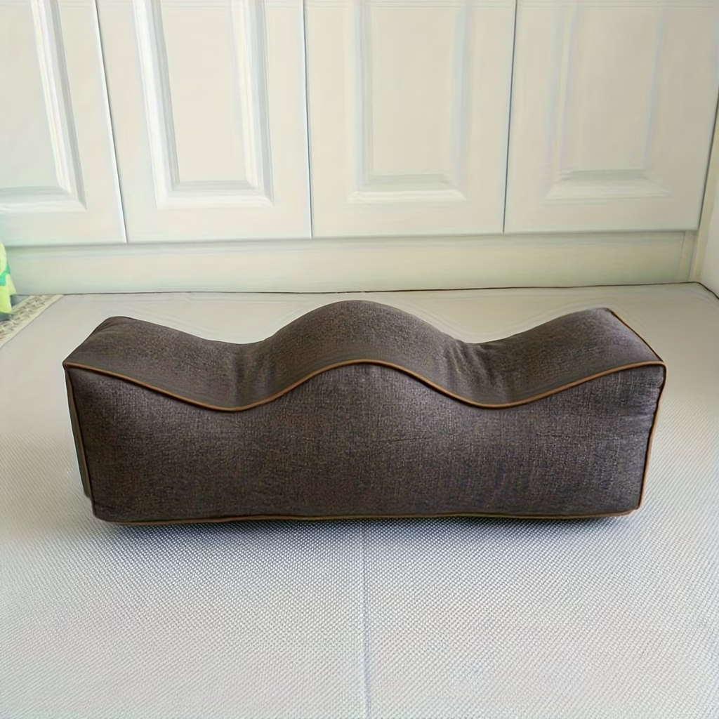 Brown linen leg support pillow with contoured top and piping, side view