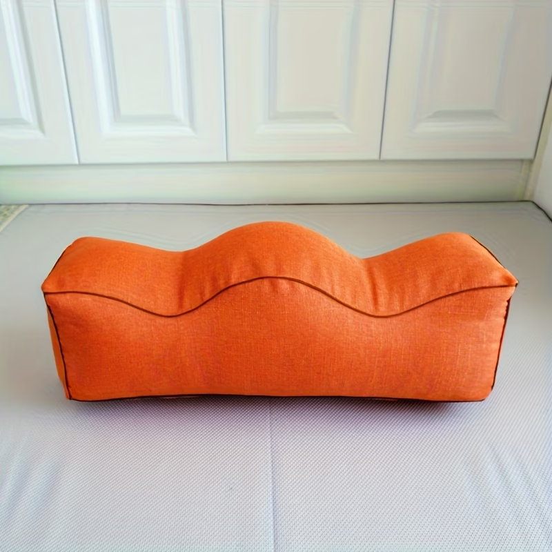Orange linen leg support pillow with wavy contoured top, side view