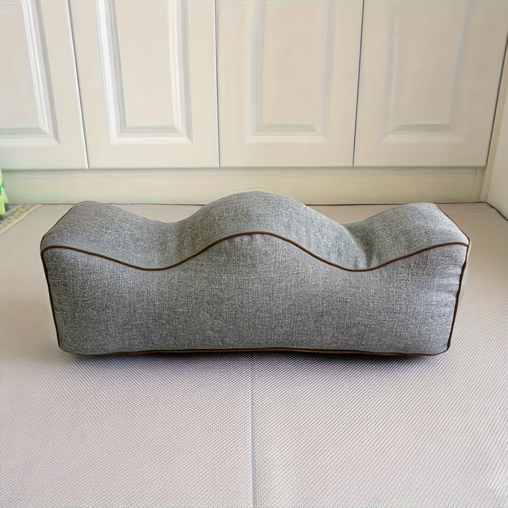 Gray linen leg elevation pillow with contoured channels and brown piping, side view